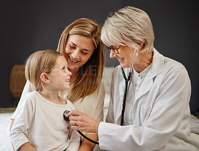 Buy stock photo Shot of a doctor examining a little girl and her mother with a stethoscope in bed at home