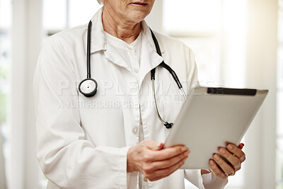 Buy stock photo Shot of a unrecognizable doctor using a digital tablet in her consulting room