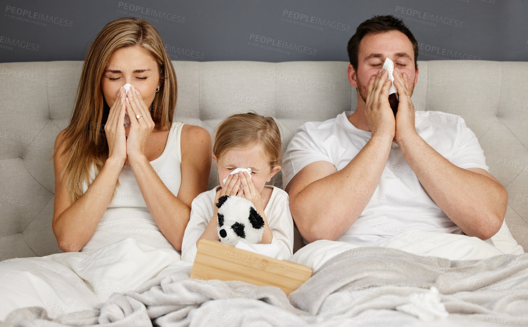 Buy stock photo Shot of a family blowing their noses while sick at home
