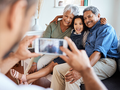Buy stock photo Shot of a photo being taken of a grandchild with her grandparents at home