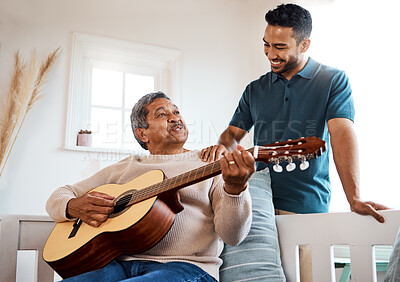 Buy stock photo Shot of a young man listening to his father play the guitar at home