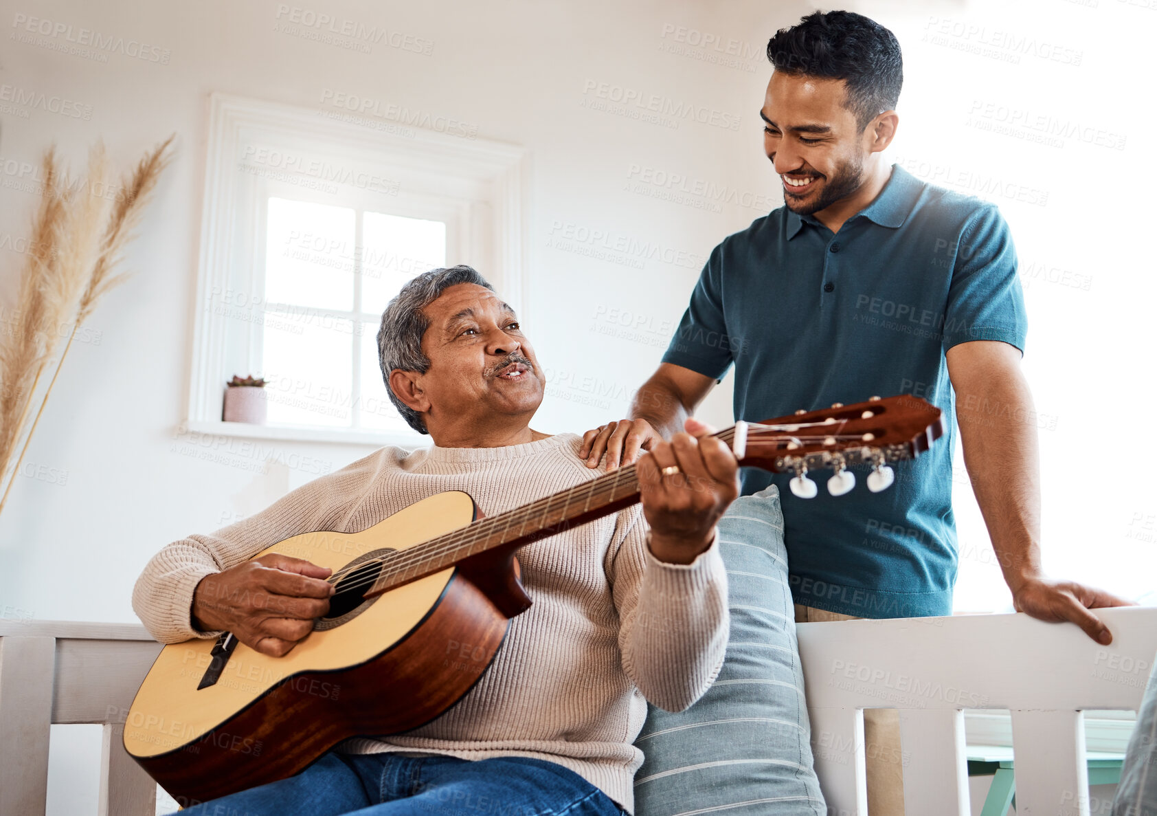 Buy stock photo Shot of a young man listening to his father play the guitar at home