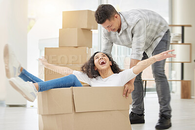 Buy stock photo Shot of a young couple feeling playful while unpacking boxes in their new home