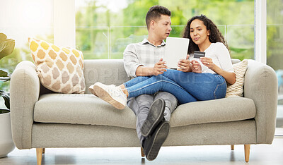 Buy stock photo Shot of a couple using a digital tablet and credit card on the sofa at home