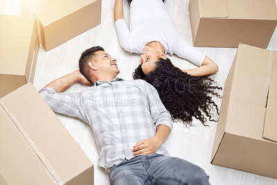 Buy stock photo Shot of a young couple lying on the floor of their new home