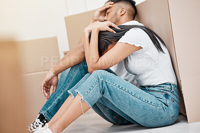 Buy stock photo Shot of a young couple sitting on the floor in their new home and feeling stressed