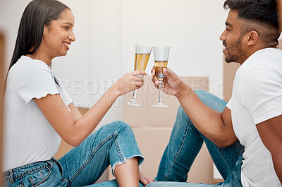 Buy stock photo Shot of a young couple sitting on the floor and celebrating their new home while drinking champagne