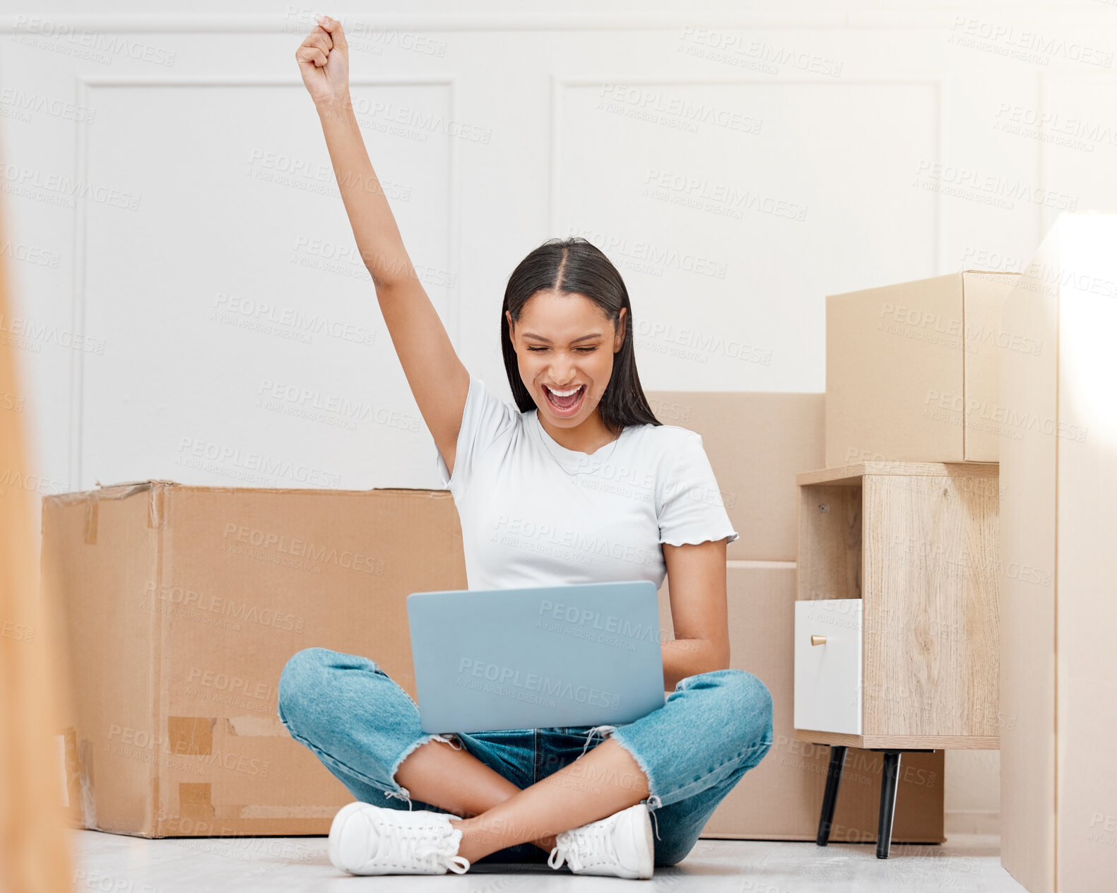 Buy stock photo Full length shot of a young woman sitting in her new home and celebrating a success while using her laptop