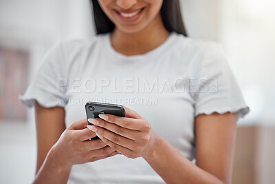 Buy stock photo Cropped shot of an unrecognisable woman standing alone in her new home and using her cellphone