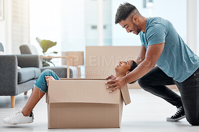 Buy stock photo Shot of a young couple feeling playful while unpacking boxes in their new home