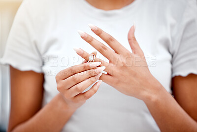 Buy stock photo Cropped shot of an unrecognisable woman standing alone and taking off her wedding ring in her new home