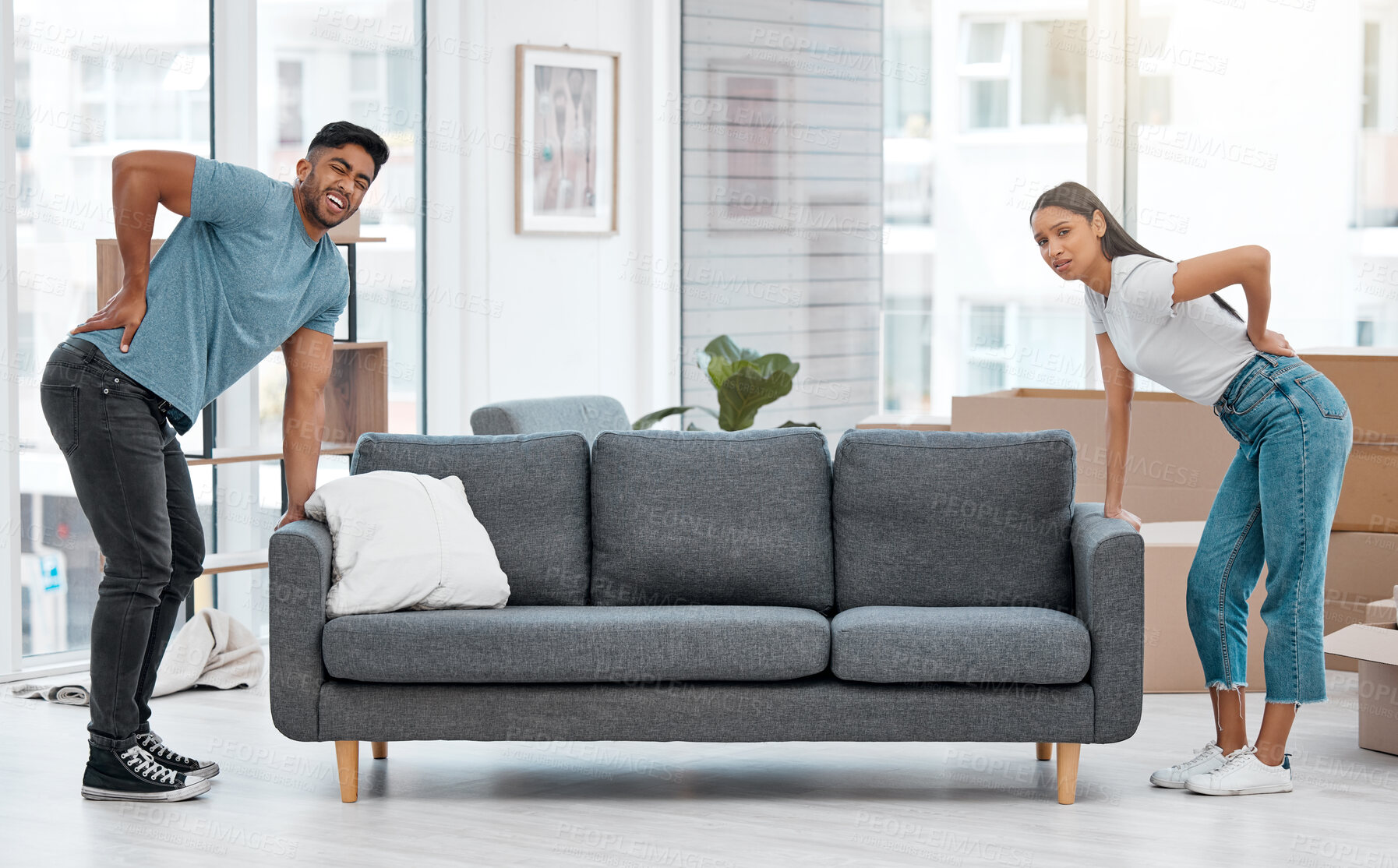 Buy stock photo Couple, back pain and moving sofa together in living room, apartment and exhausted. Furniture, man and woman with heavy couch in property, backache and packing  for relocation inside the house 