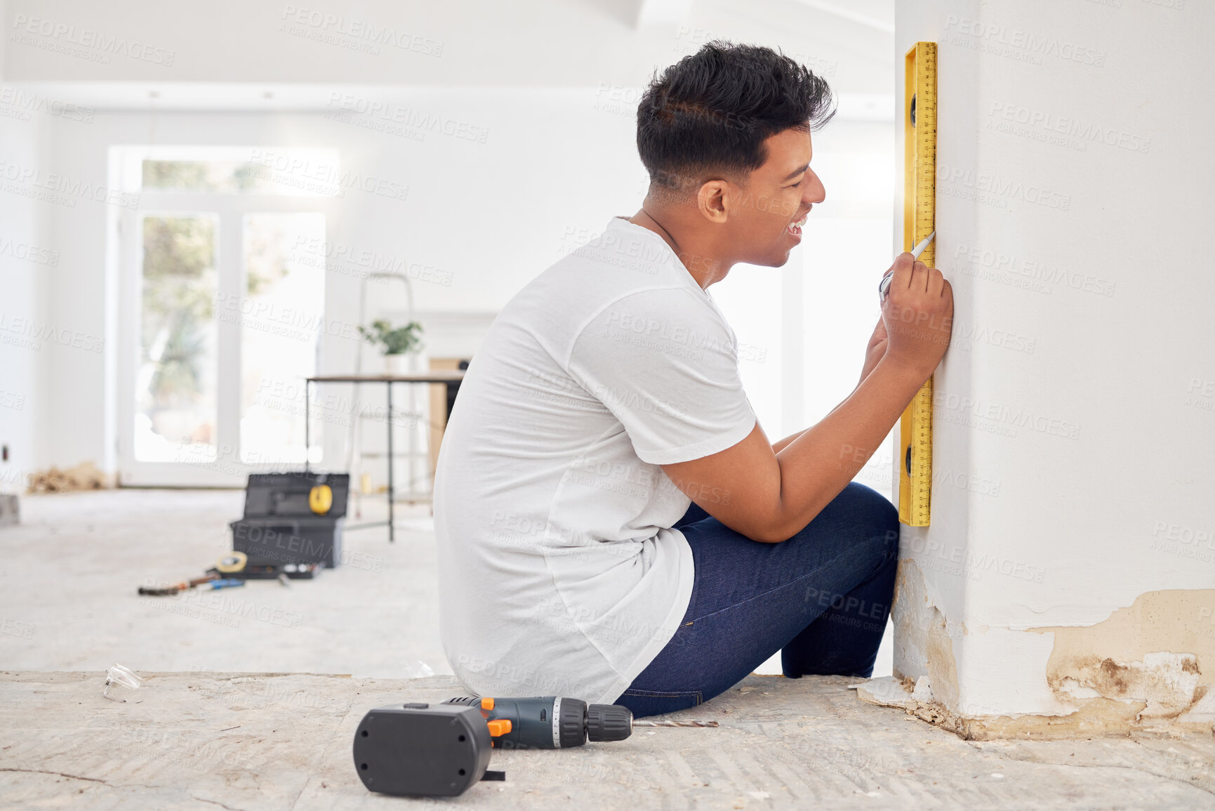 Buy stock photo DIY, happy man and level at wall for maintenance, project and home renovation in apartment. Handyman, equipment and smile in living room for installation, interior design and carpentry or remodeling