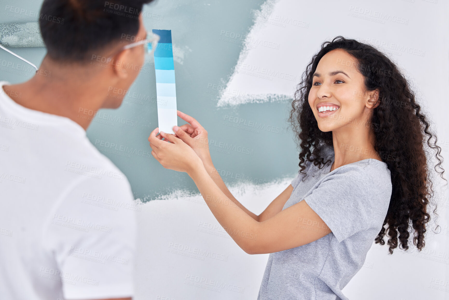 Buy stock photo Shot of a young couple looking at a color swatch while busy renovating a house