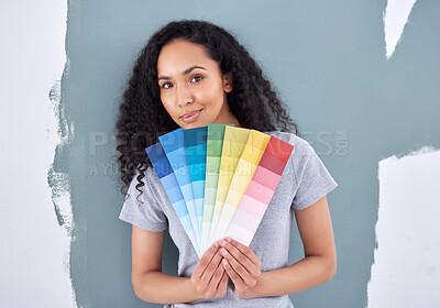 Buy stock photo Shot of a woman holding up color swatches while standing against a painted wall