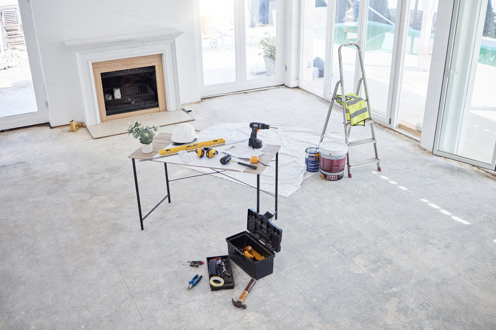 Buy stock photo High angle shot of building plans and equipment on a table in an empty living room during the day