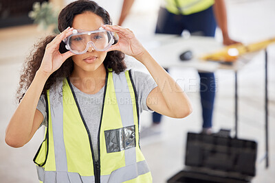 Buy stock photo Shot of an attractive young contractor standing inside and putting safety goggles on