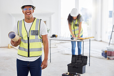 Buy stock photo Shot of a handsome young contractor standing inside and holding building plans