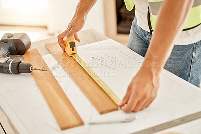 Buy stock photo Cropped shot of an unrecognisable construction worker standing alone and using measuring tape to measure a beam of wood