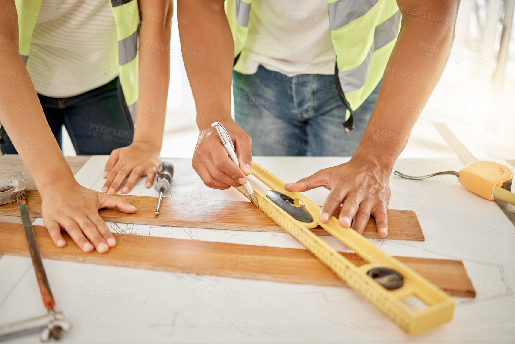 Buy stock photo Cropped shot of two unrecognisable construction workers standing together and using a ruler to measure a beam of wood