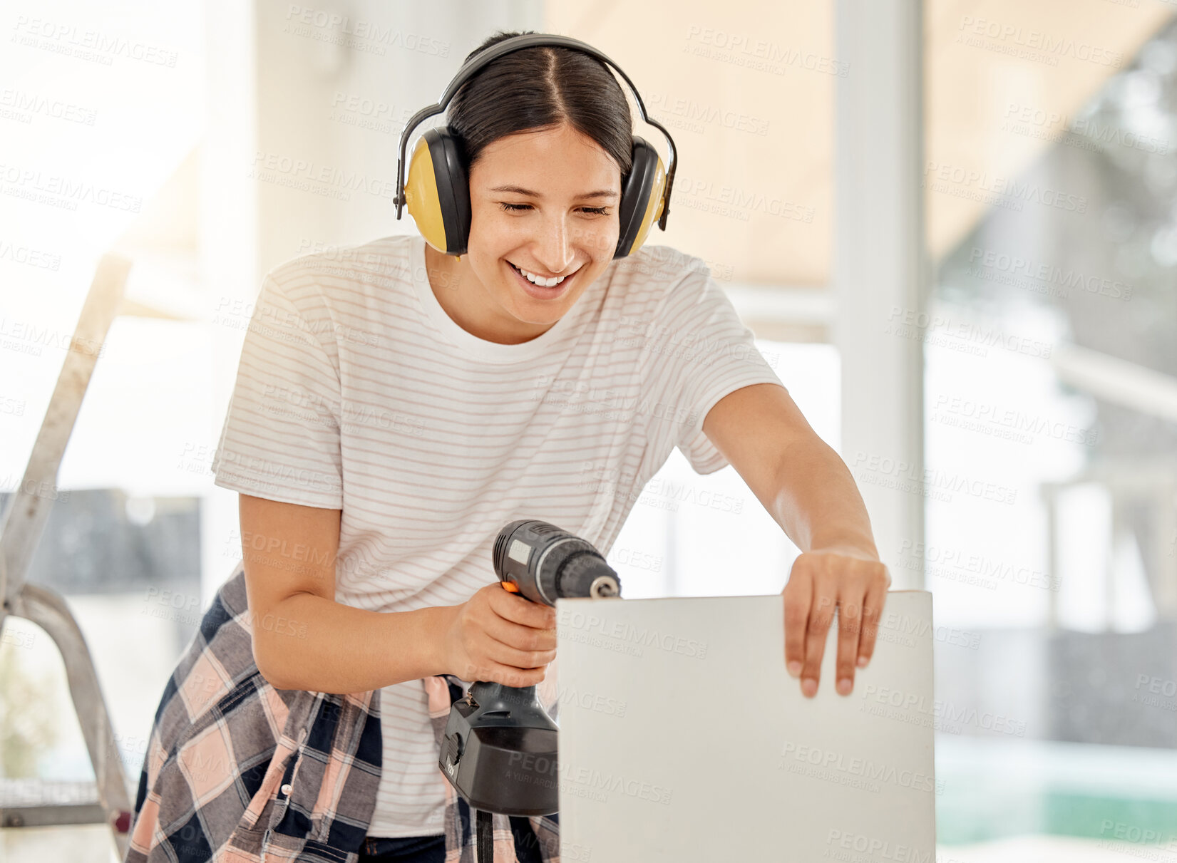 Buy stock photo Shot of an attractive young woman standing alone in her home and using a power drill