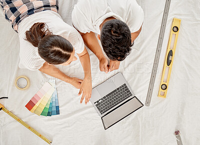 Buy stock photo High angle shot of an unrecognisable couple lying on their living room floor and using a laptop