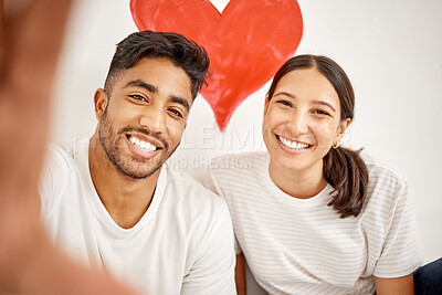 Buy stock photo Shot of a young couple taking a selfie with a red heart in the background