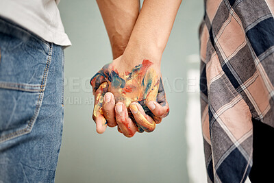 Buy stock photo Cropped shot of an unrecognizable couple standing hand in hand while painting at home