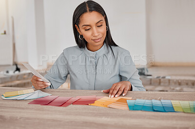 Buy stock photo Shot of a young woman looking at different colour swatches while renovating her house