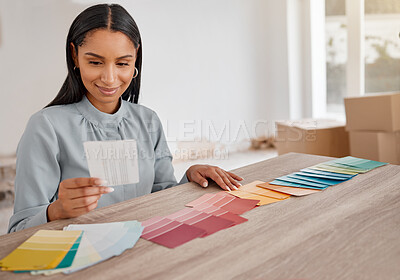 Buy stock photo Shot of a young woman looking at different colour swatches while renovating her house