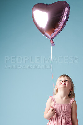 Buy stock photo Heart balloon, happiness and girl in studio for mockup, celebration and love for family. Female child, festive and smile by blue background for event, party and special holiday or remembrance