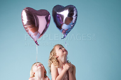 Buy stock photo Children, love and sister with heart balloon in studio on blue background for family or party. Birthday, celebration or smile with happy girl kids and youth on color backdrop together for event