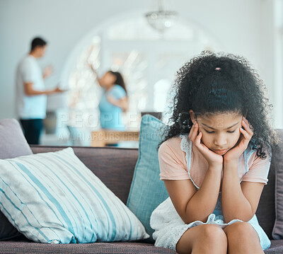 Buy stock photo Shot of a little girl looking sad on a sofa while her parents argue in the background