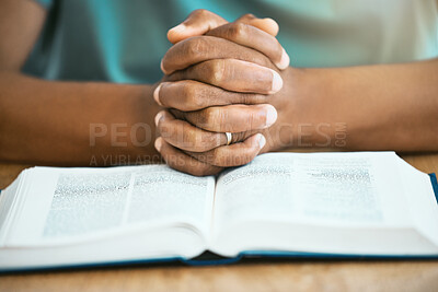 Buy stock photo Hands, person and praying with bible in home with worship, spiritual practice and gratitude at table. Christianity, guidance and holy book for praise to God, forgiveness and thankful in living room