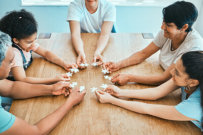 Buy stock photo Shot of a family building a puzzle together at home