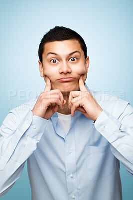 Buy stock photo Man, hands and facial expression for portrait in studio as creative comedian with funny gesture for amusement. Playful, male person and comedy as career on blue background for humour with jokes