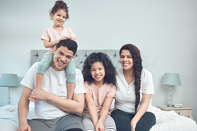 Buy stock photo Portrait of a beautiful young family talking and bonding while sitting on a bed together