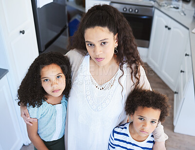 Buy stock photo Shot of a young mother holding her children while standing in the kitchen at home
