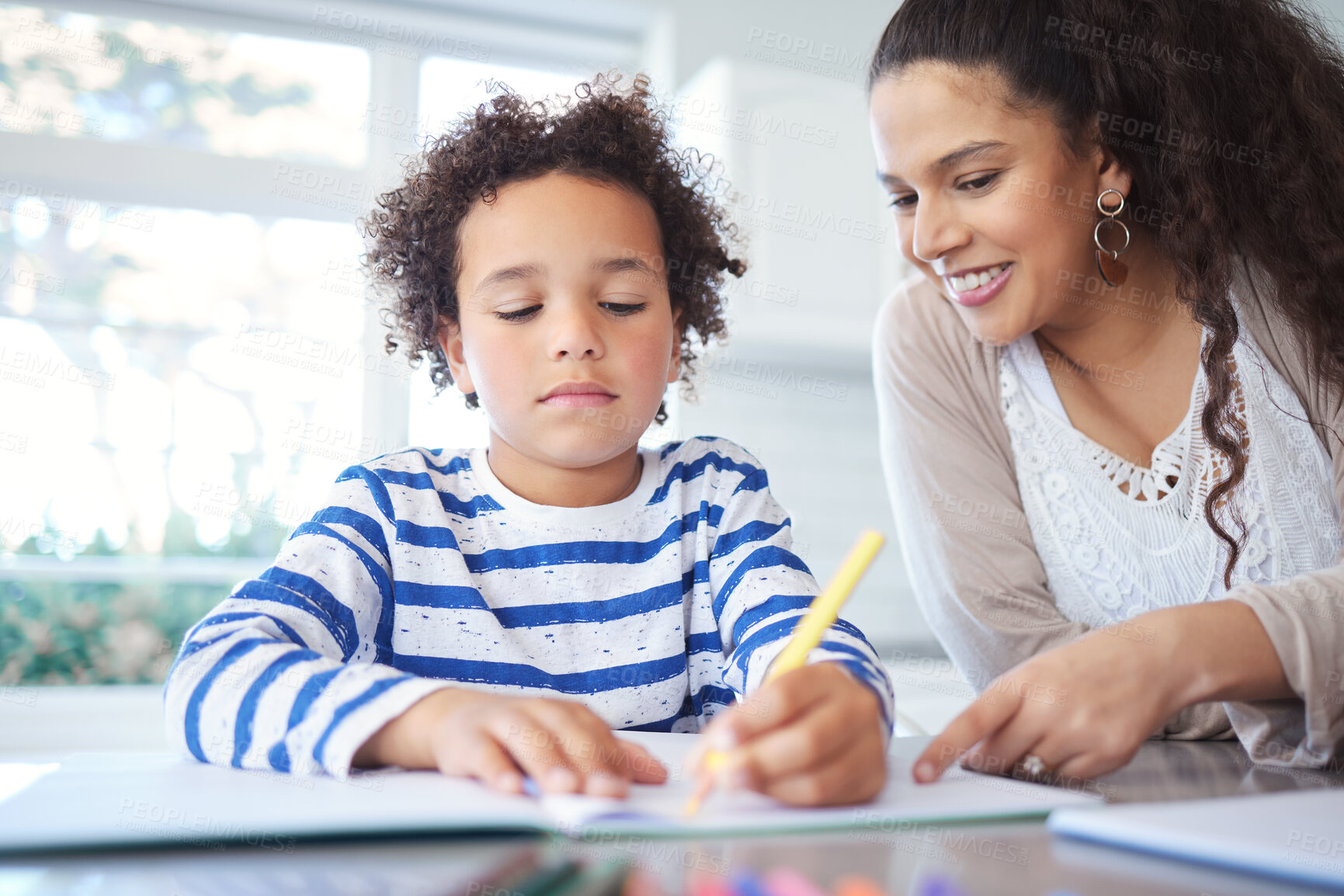 Buy stock photo Shot of a mother helping her son with homework at the kitchen table