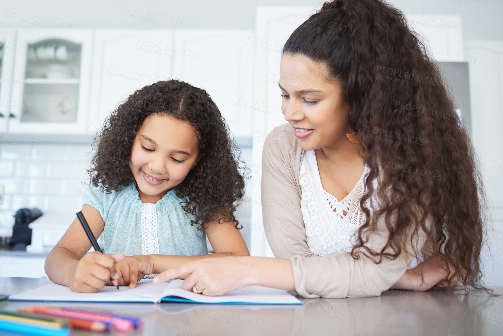 Buy stock photo Shot of a mother helping her daughter with homework at the kitchen table
