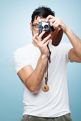 Buy stock photo Shot of a young male photographer taking photos against a studio background