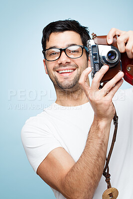 Buy stock photo Portrait, man and photographer with camera in studio for picture, creative media and memory as artistic session. Smile, male paparazzi and vintage digital tech for production film on blue background