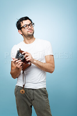 Buy stock photo Thinking, man and photographer with camera in studio for picture, creative media and memory as artistic reporter. Male paparazzi, idea and vintage digital tech for production film on blue background