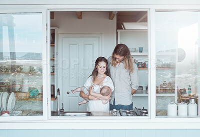 Buy stock photo Shot of a young family holding their newborn affectionately in the kitchen at home