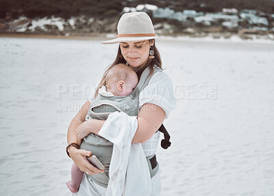 Buy stock photo Shot of a young mother holding her baby while at the beach