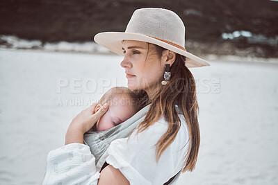 Buy stock photo Shot of a young mother holding her baby while at the beach