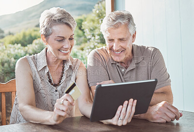 Buy stock photo Shot of a mature couple sitting together while using a digital tablet and a credit card