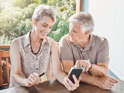 Buy stock photo Shot of a mature couple sitting together while using a cellphone and a credit card
