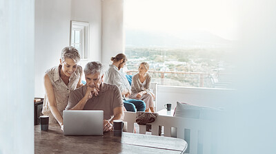 Buy stock photo Shot of a mature couple using a laptop at home while a young couple sits in the background