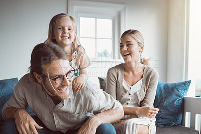 Buy stock photo Shot of a young couple and their daughter sitting together at home